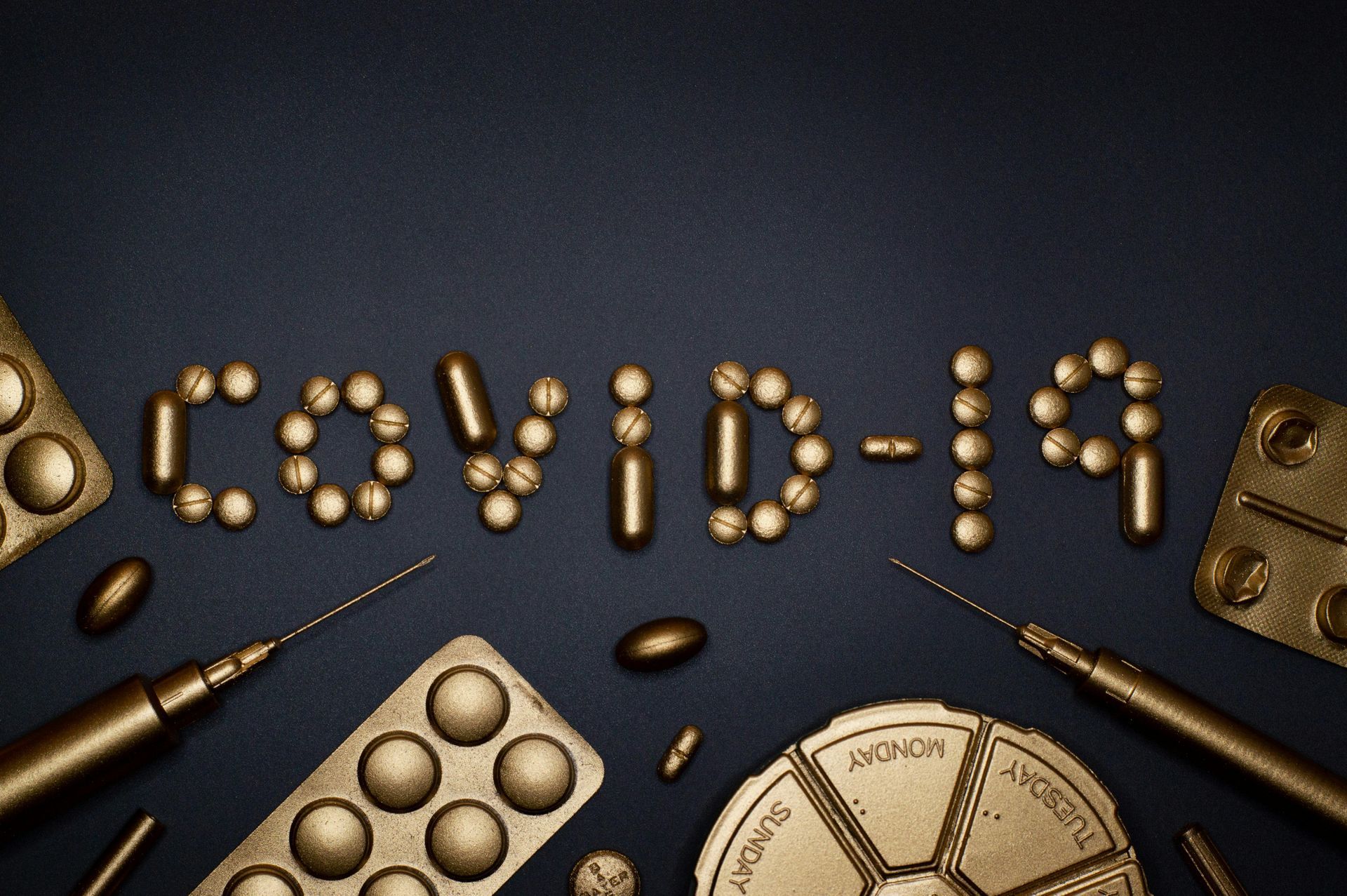 The word covid-19 is made out of pills and syringes on a table.