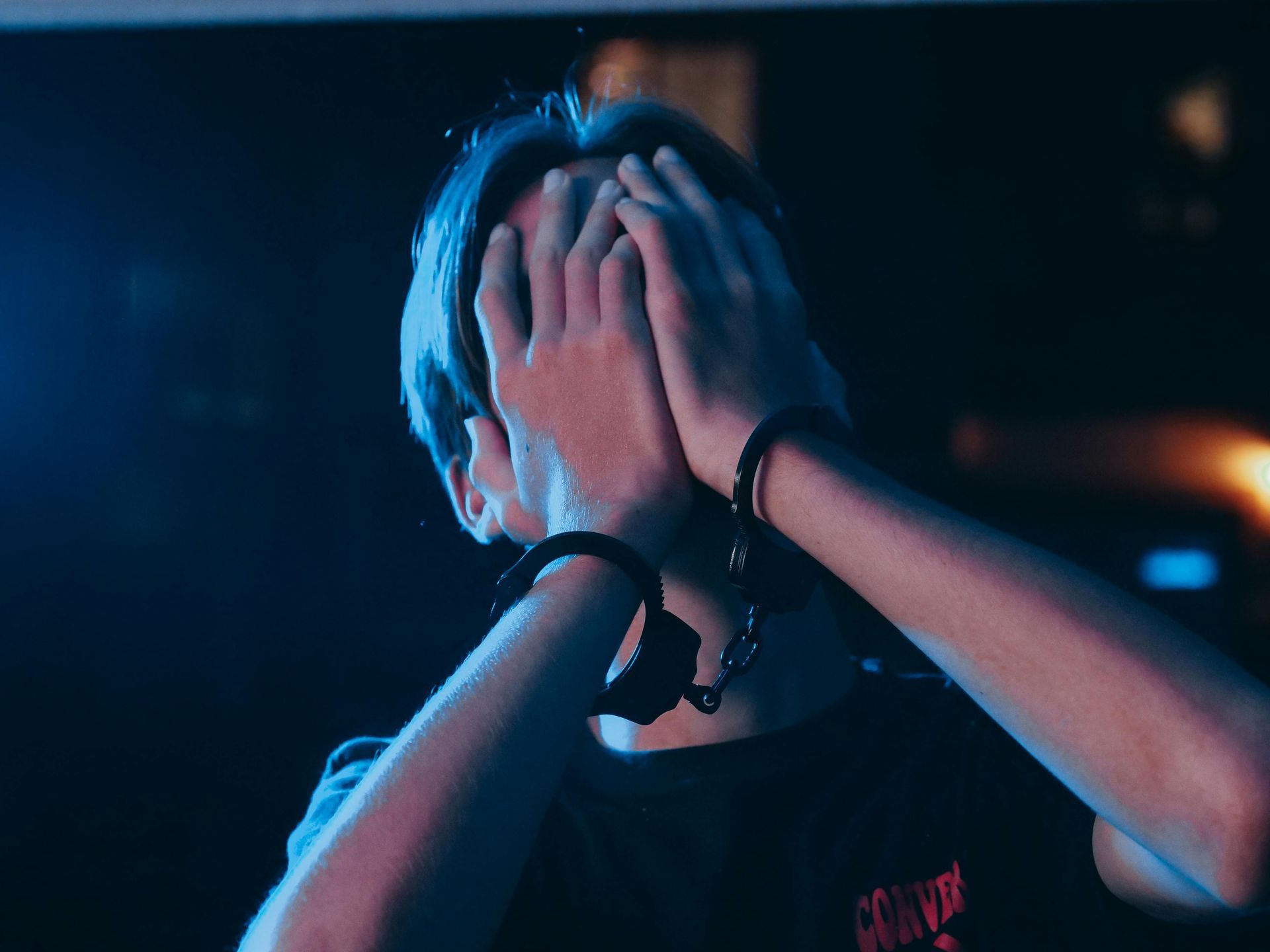 A picture of a person who has his hands cuffed and over his face in disbelief.