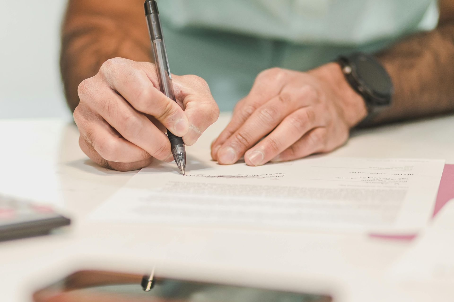 A man is writing on a piece of paper with a pen. 