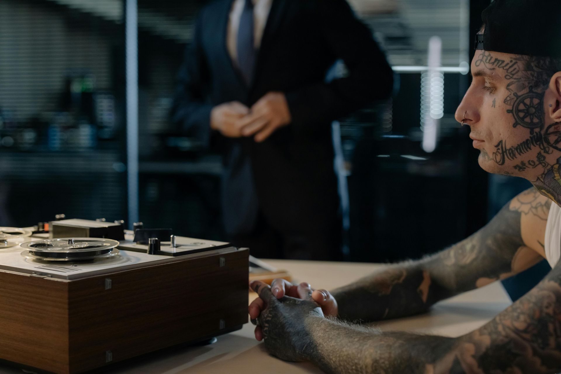 A man with tattoos is sitting at a table with a tape recorder.