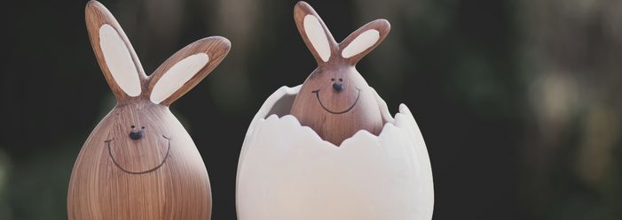 Páscoa na empresa foto de dois coelhos feito de madeira e um deles saindo de uma casa de ovo