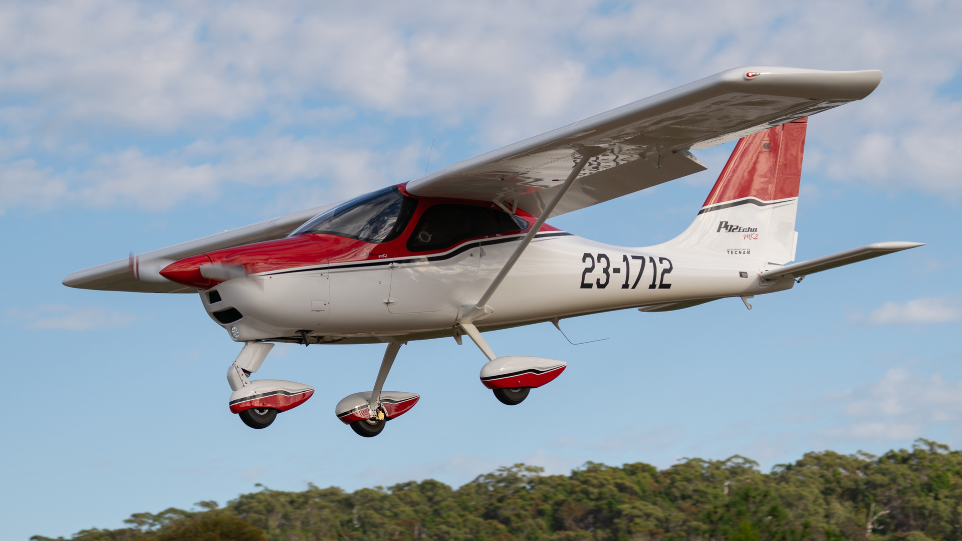 A small red and white plane is flying in the sky.