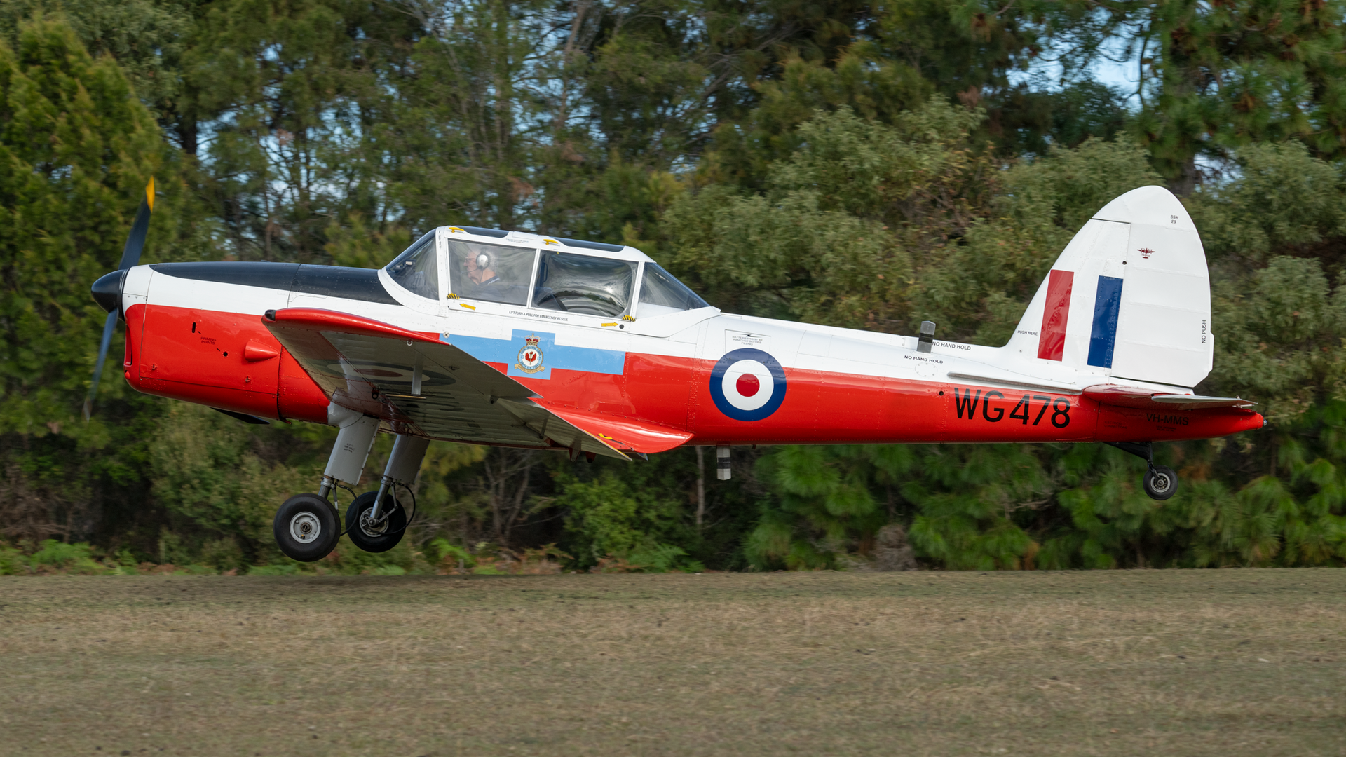 A small red and white airplane is taking off from a runway.