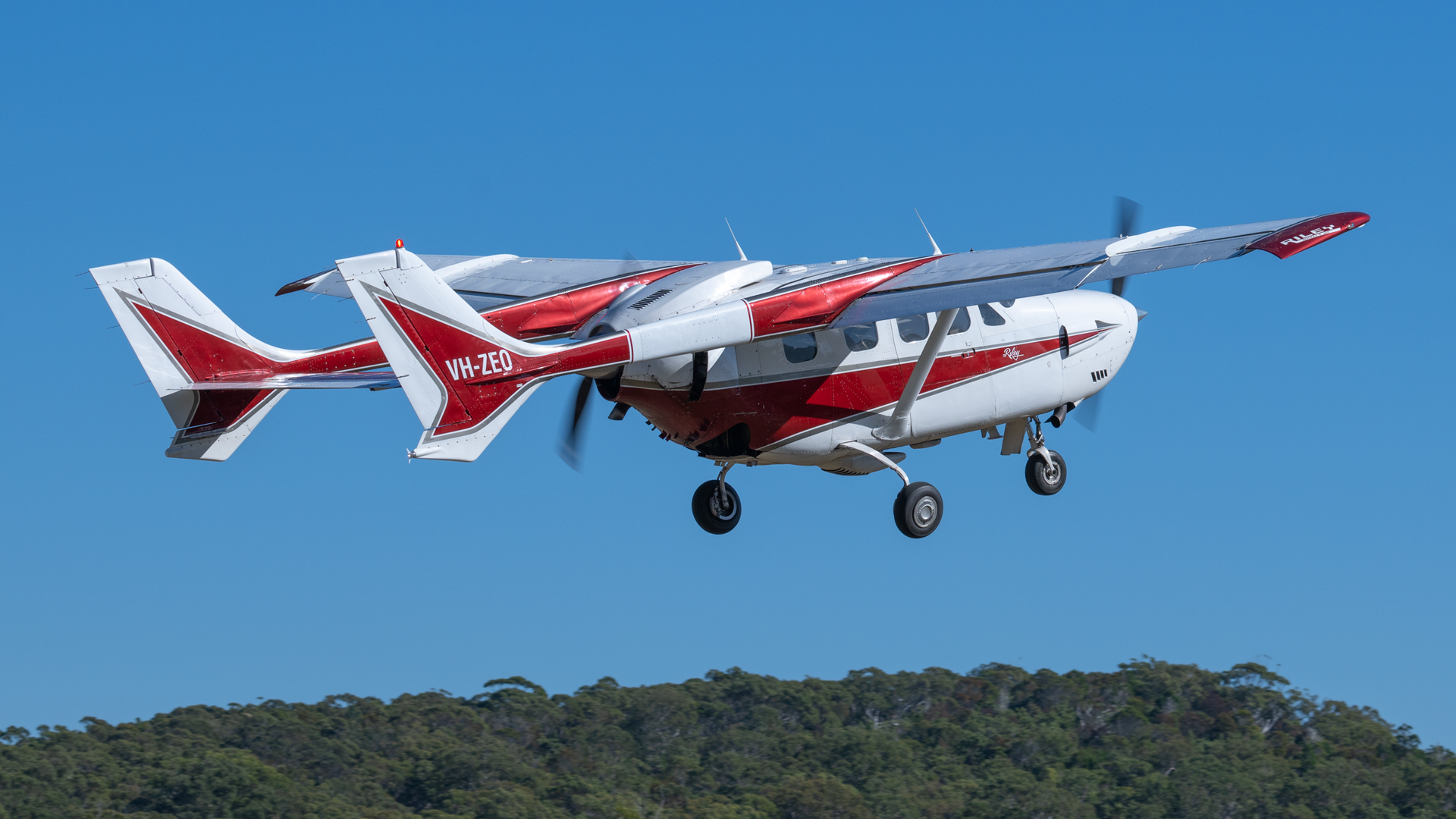 A small red and white plane is flying in the sky