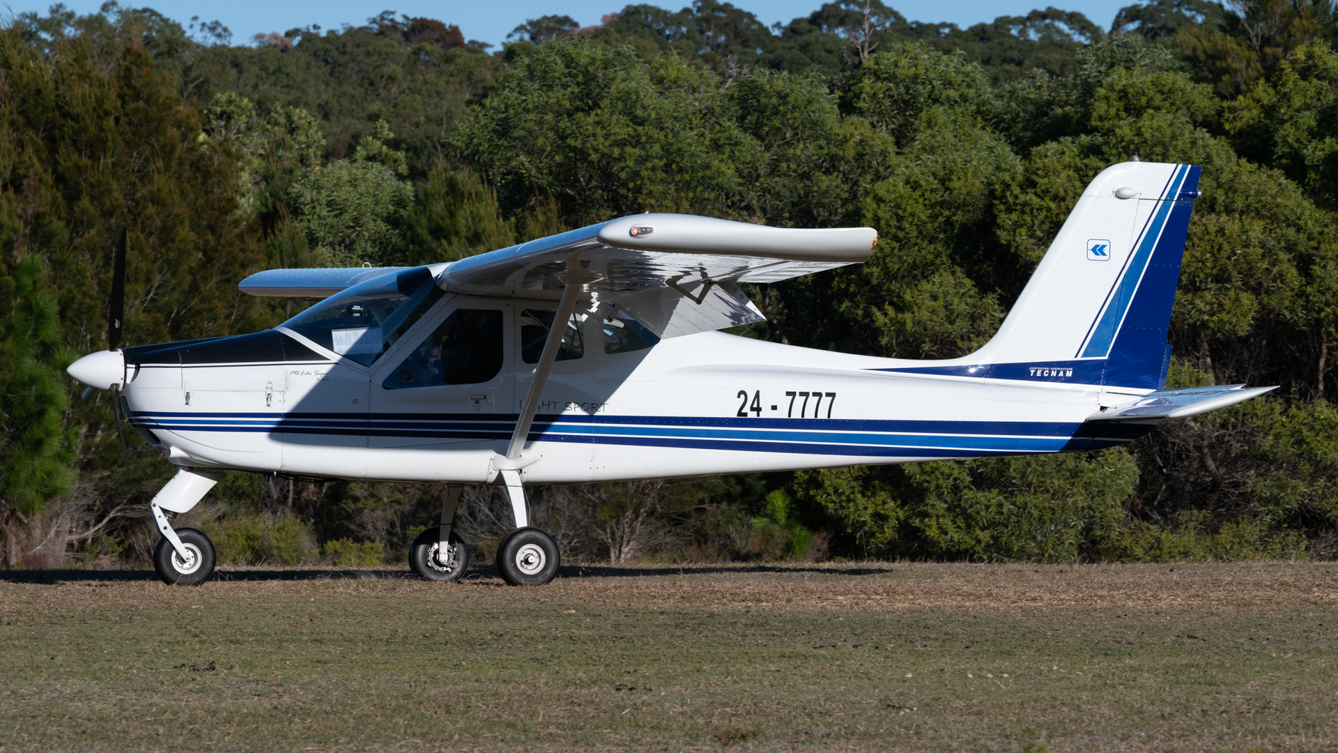 A small blue and white plane with the number 24-7727 on the side