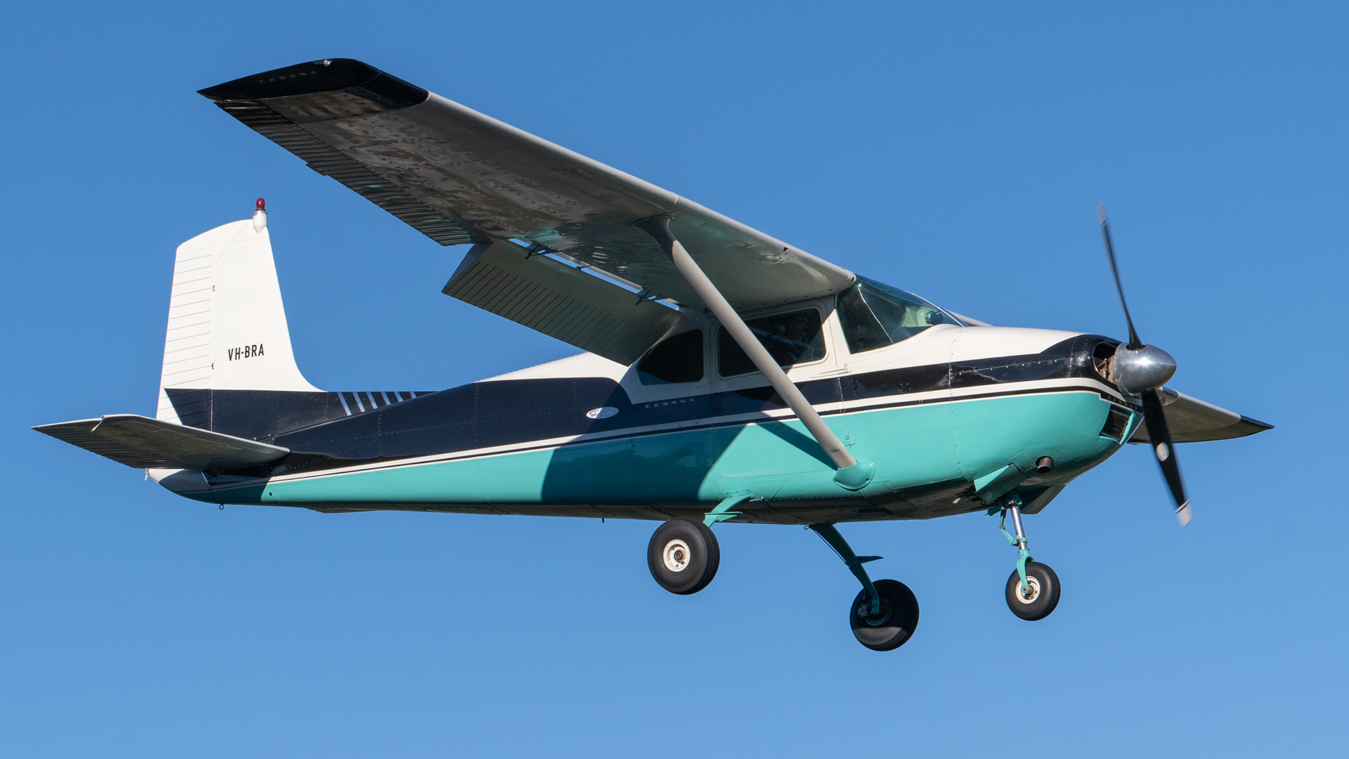 A small blue and white plane is flying in the sky