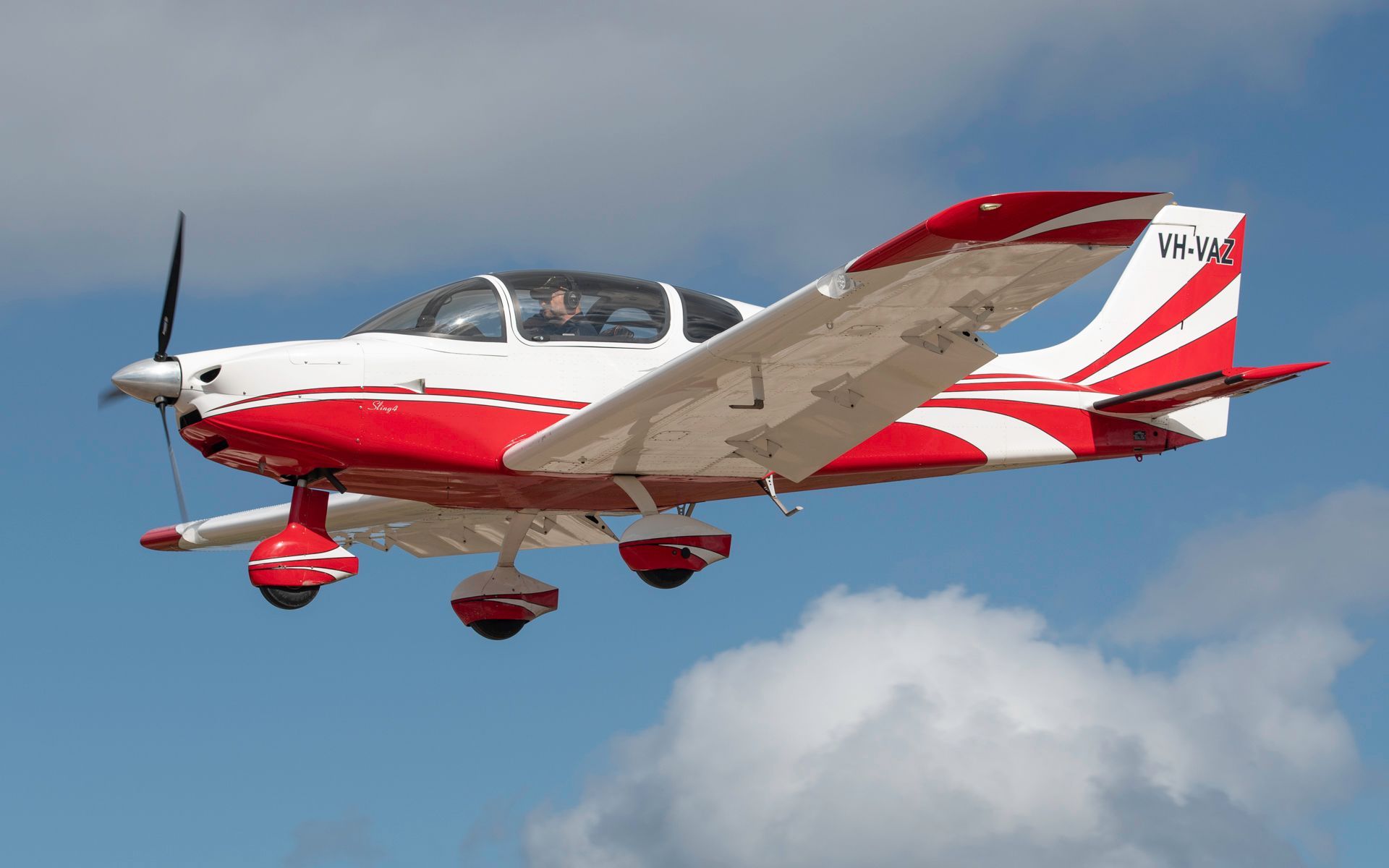 a small red and white plane is flying in the sky