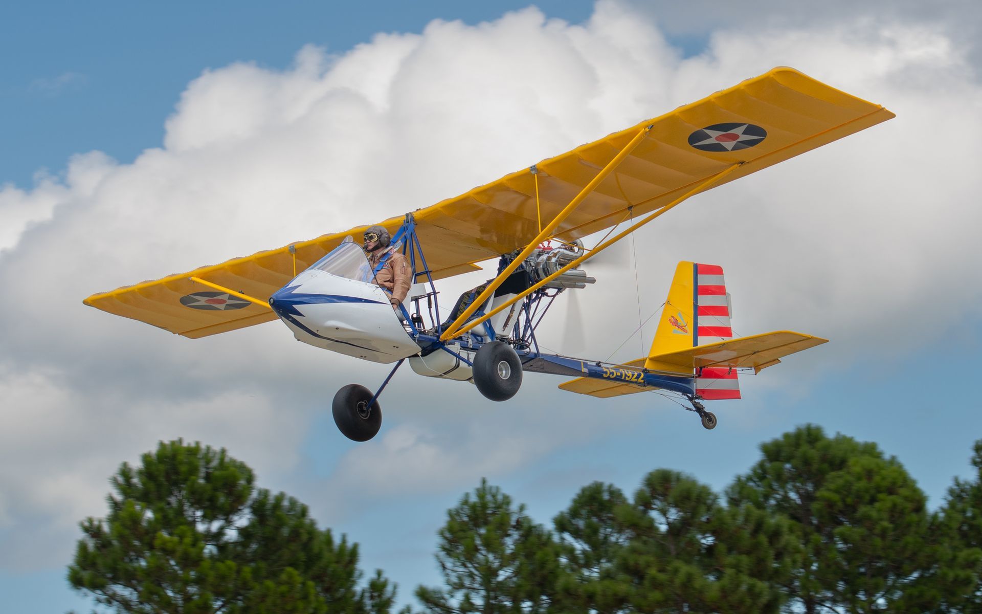 a small plane is flying in the sky over trees
