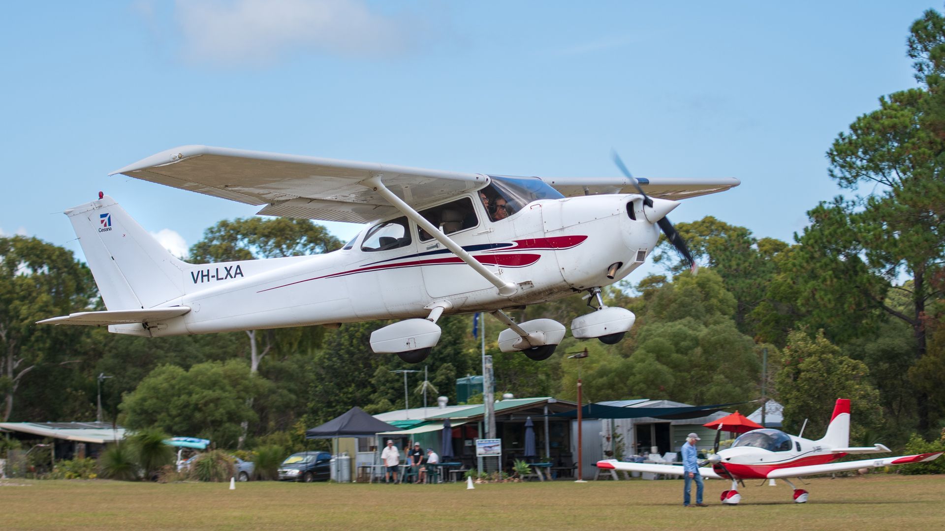 a small plane is taking off from a grassy field