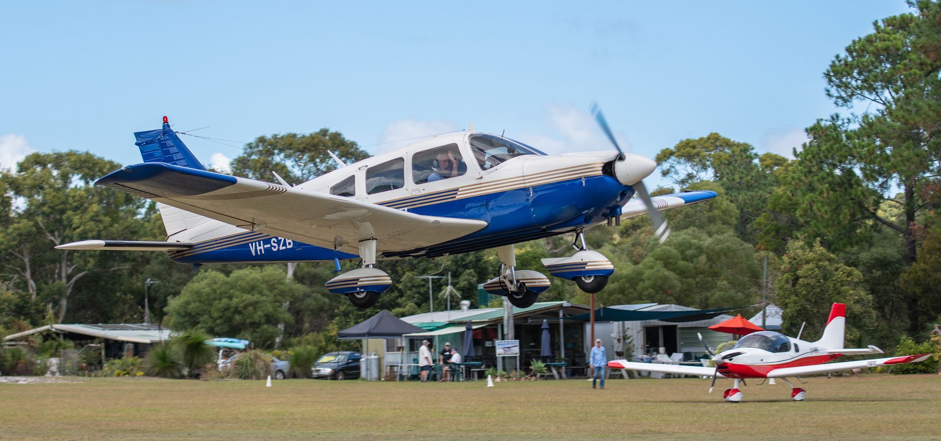 a blue and white plane is taking off from a runway .