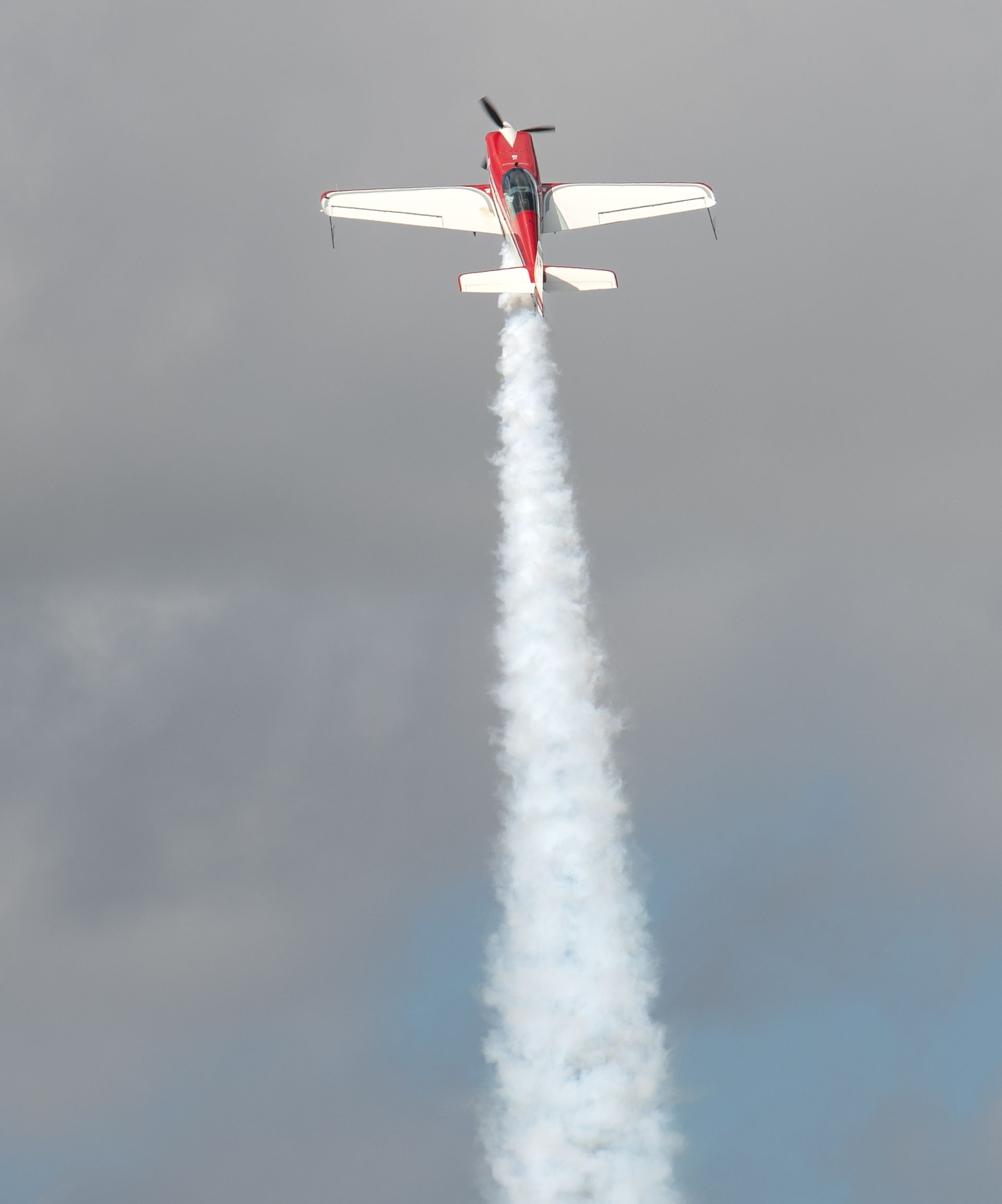 a red and white airplane is flying through a cloudy sky