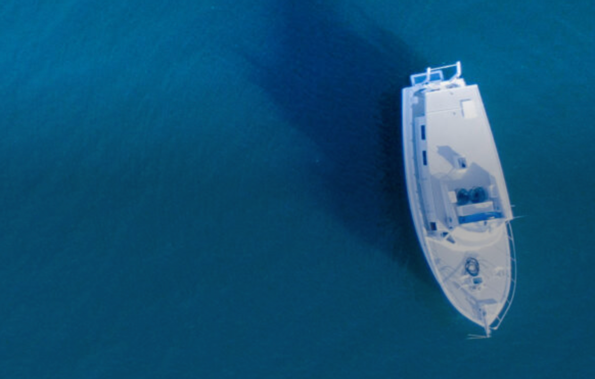 an aerial view of a white boat in the middle of the ocean .