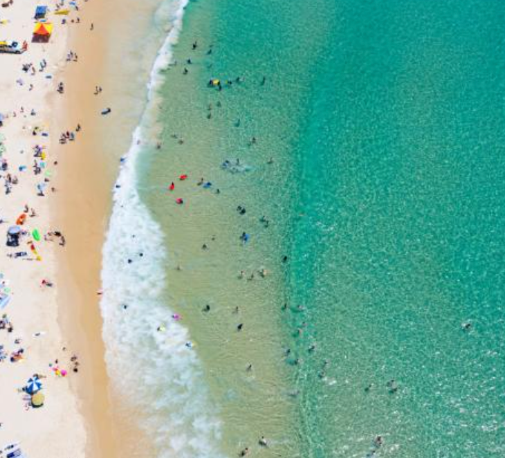 An aerial view of a beach filled with people and waves.