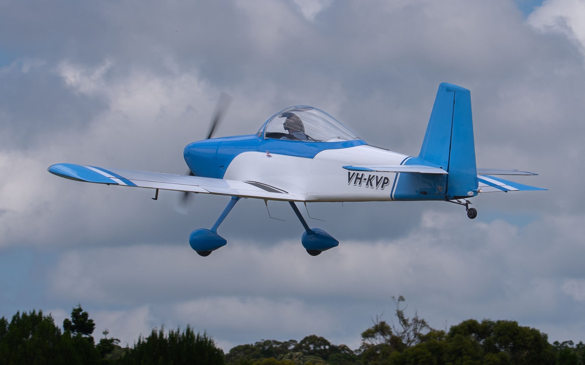 a small blue and white plane is flying in the sky .