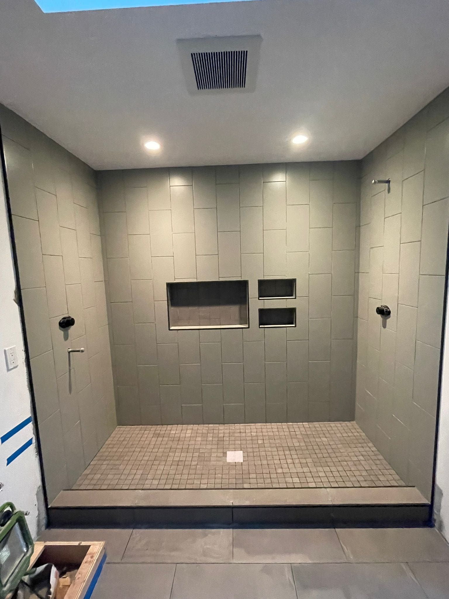 A bathroom under construction with a walk in shower and a skylight.