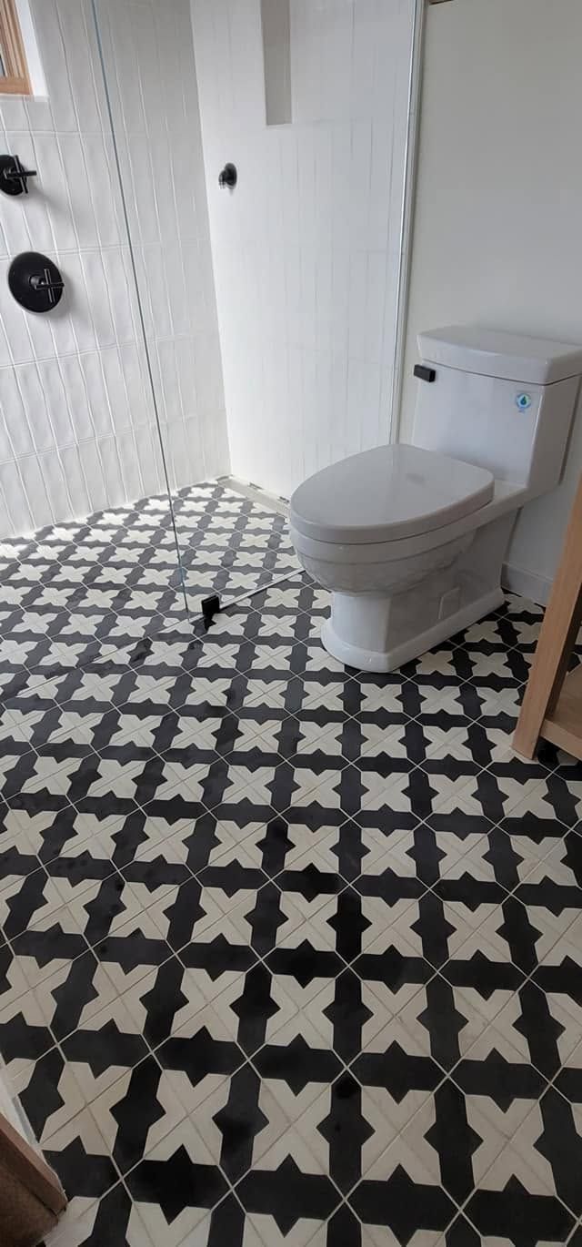 A bathroom with a black and white tile floor and a toilet.