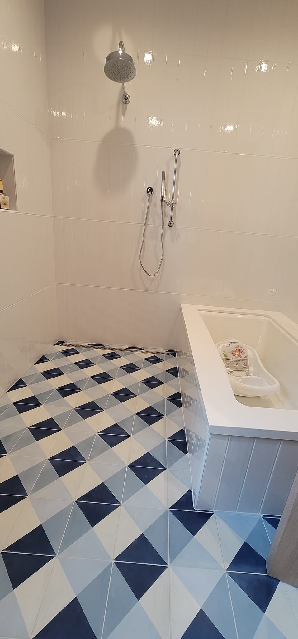 A bathroom with a bathtub , shower , and checkered floor.