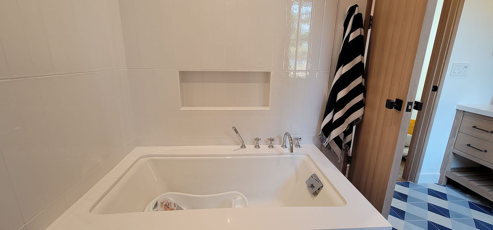 A bathroom with a bathtub and a towel hanging on the door.