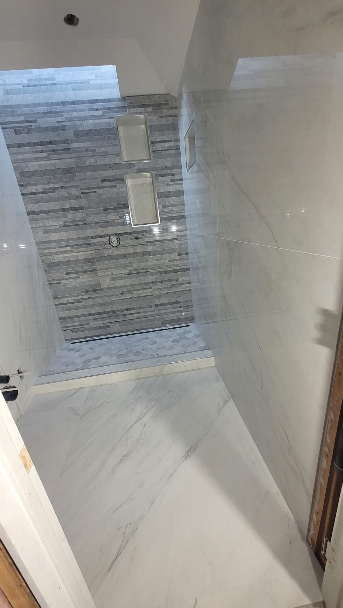 A bathroom with white tiles and a stone wall.