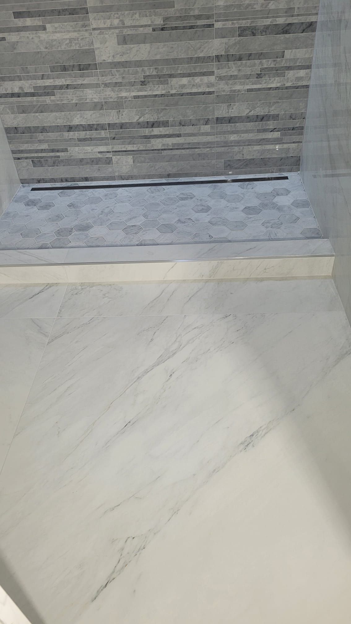 A bathroom with a walk in shower and a tiled floor.