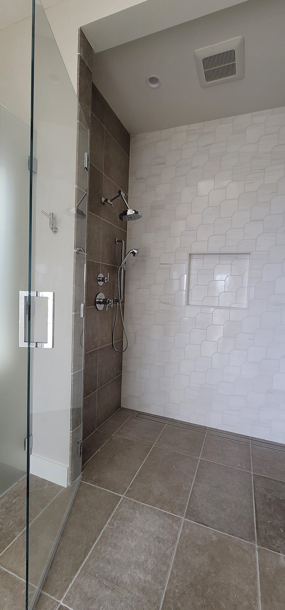 A bathroom with a walk in shower and a glass door.