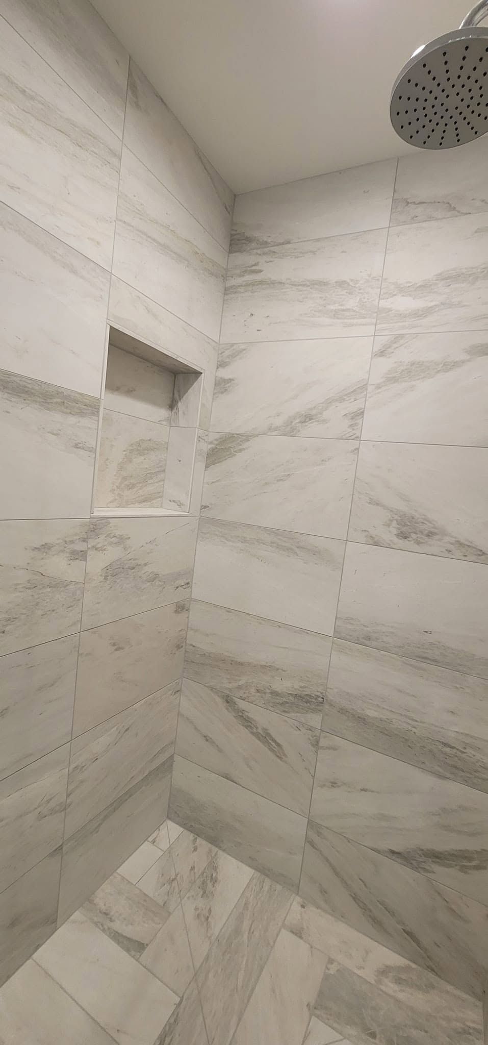 A shower with marble tiles and a shower head.