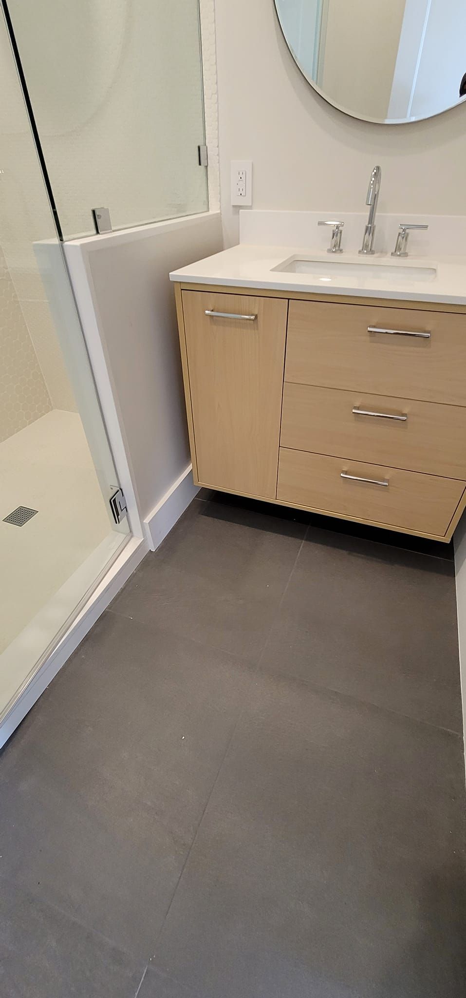 A bathroom with a sink , mirror and walk in shower.