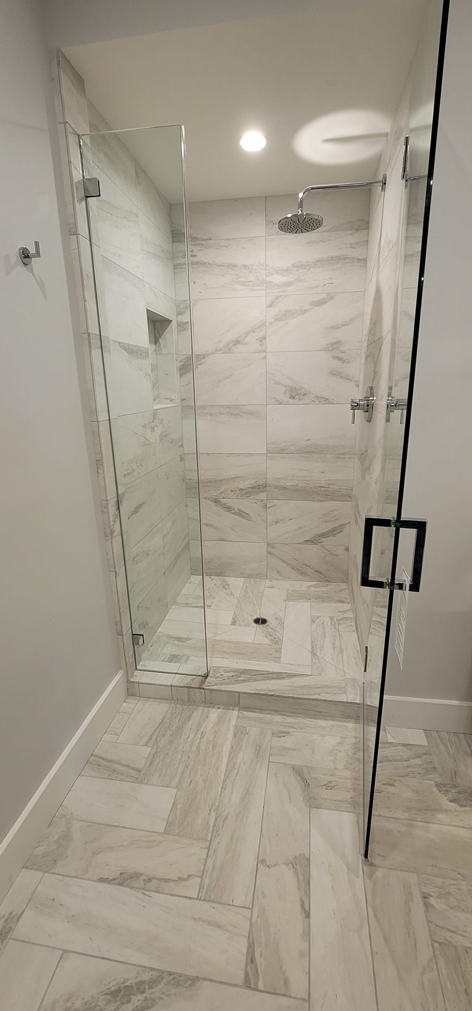 A bathroom with a walk in shower with a glass door.