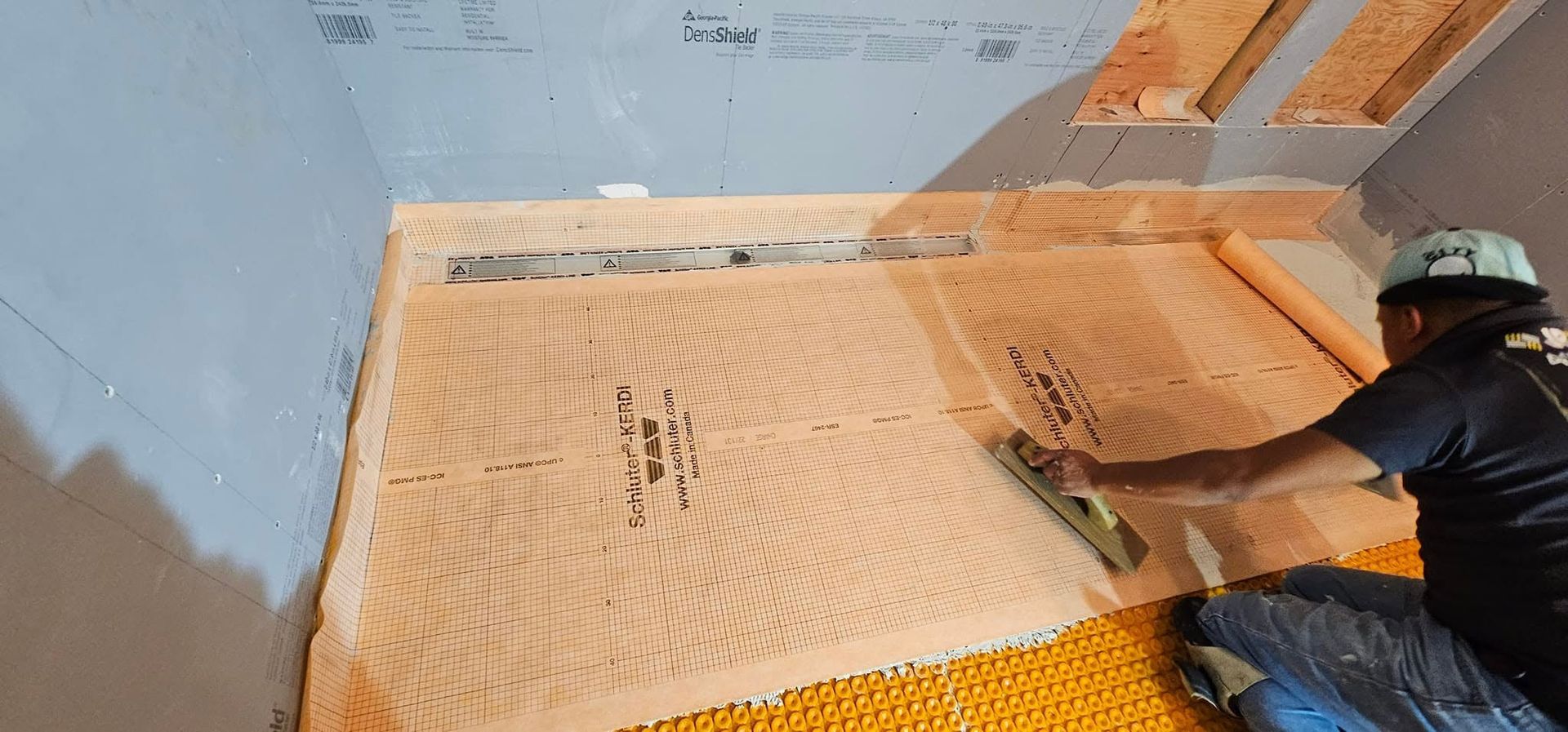 A man is kneeling on the floor using a trowel.