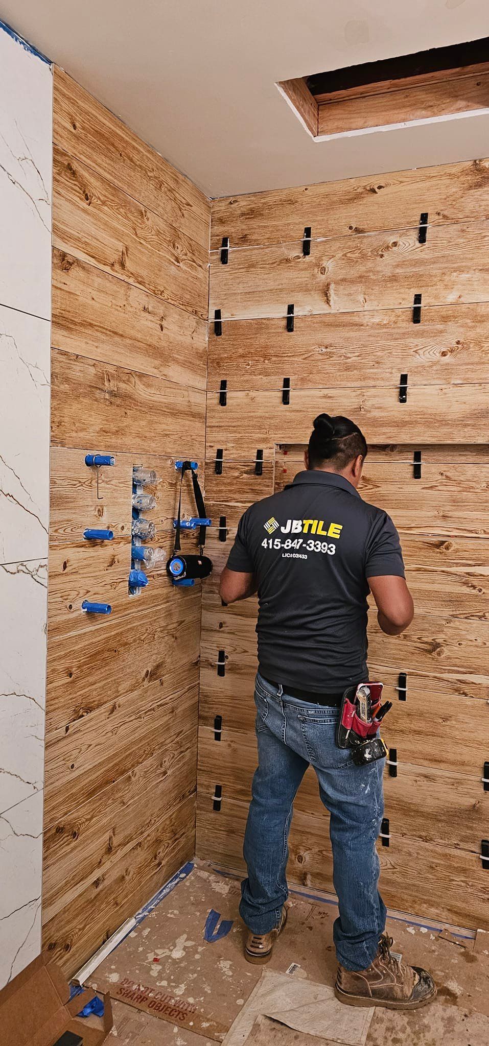 A man is working on a wooden wall in a room.