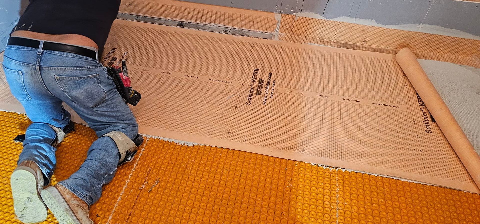 A man is laying a yellow mat on the floor.