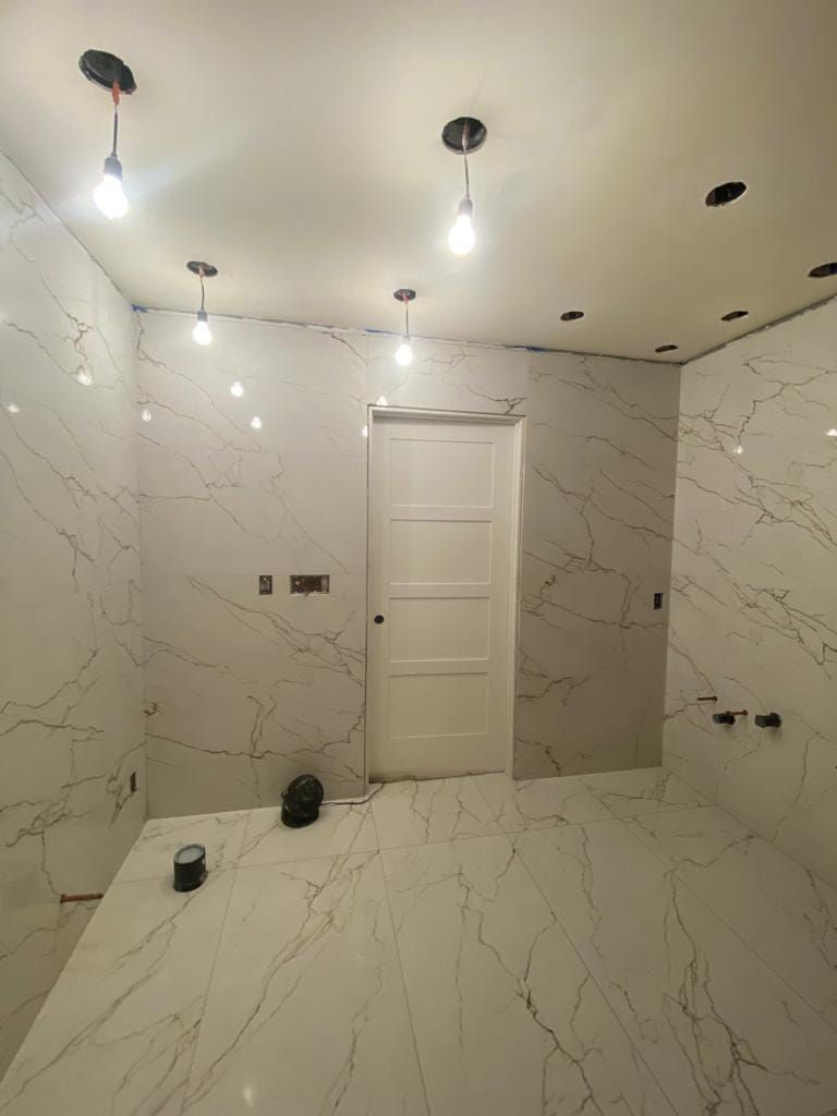 A bathroom with white tiles and a white door.