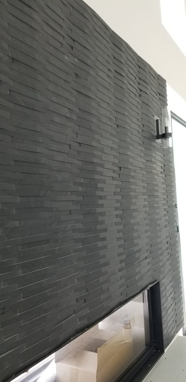 A black brick wall with a fireplace in a living room.