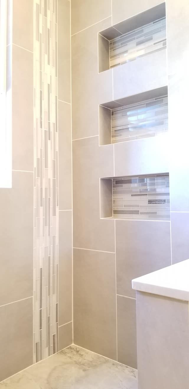 A bathroom with a walk in shower and built in shelves.