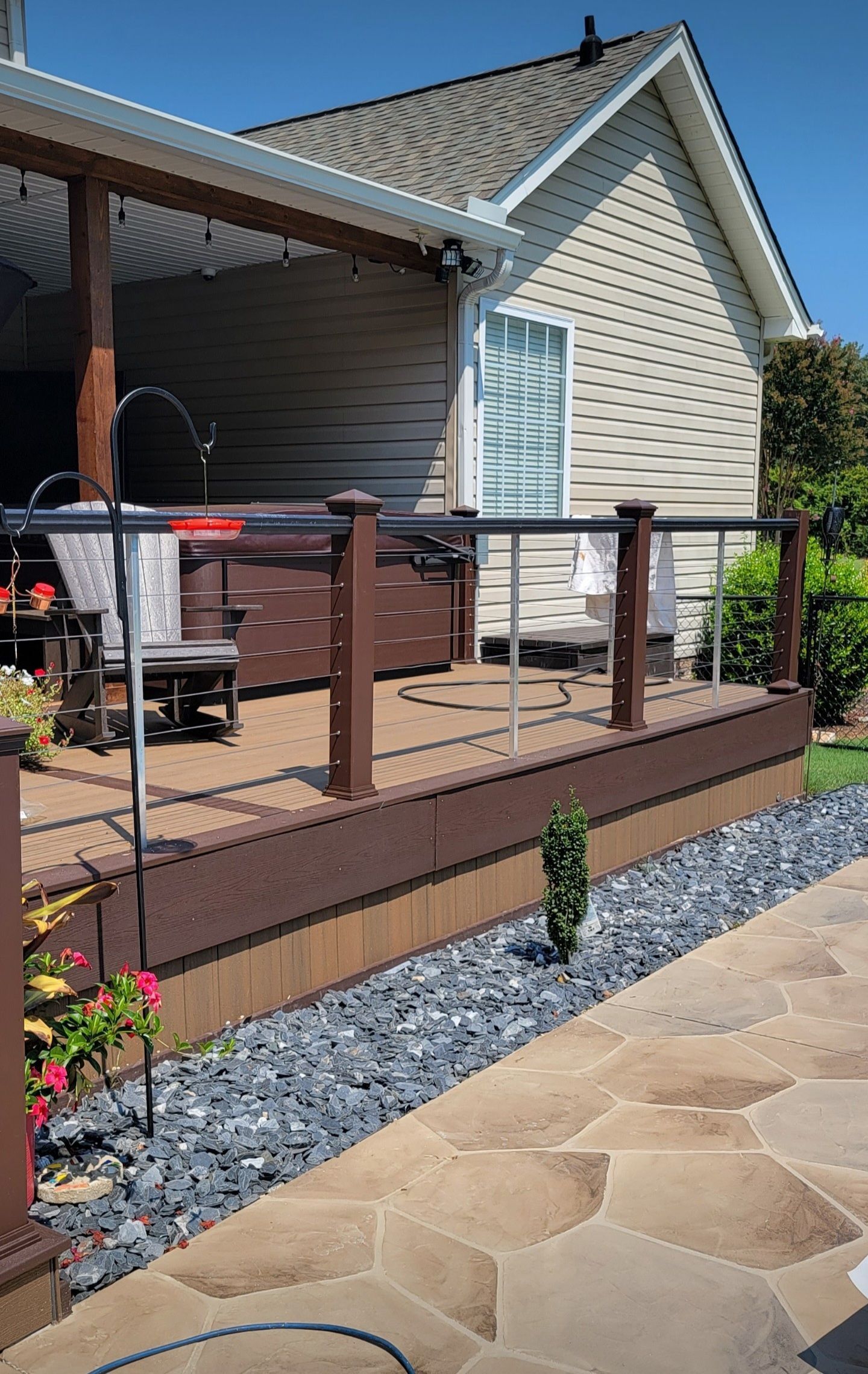 Above-ground pool with deck. Brown composite decking surrounds the blue pool. Lounge chairs and seating areas visible.