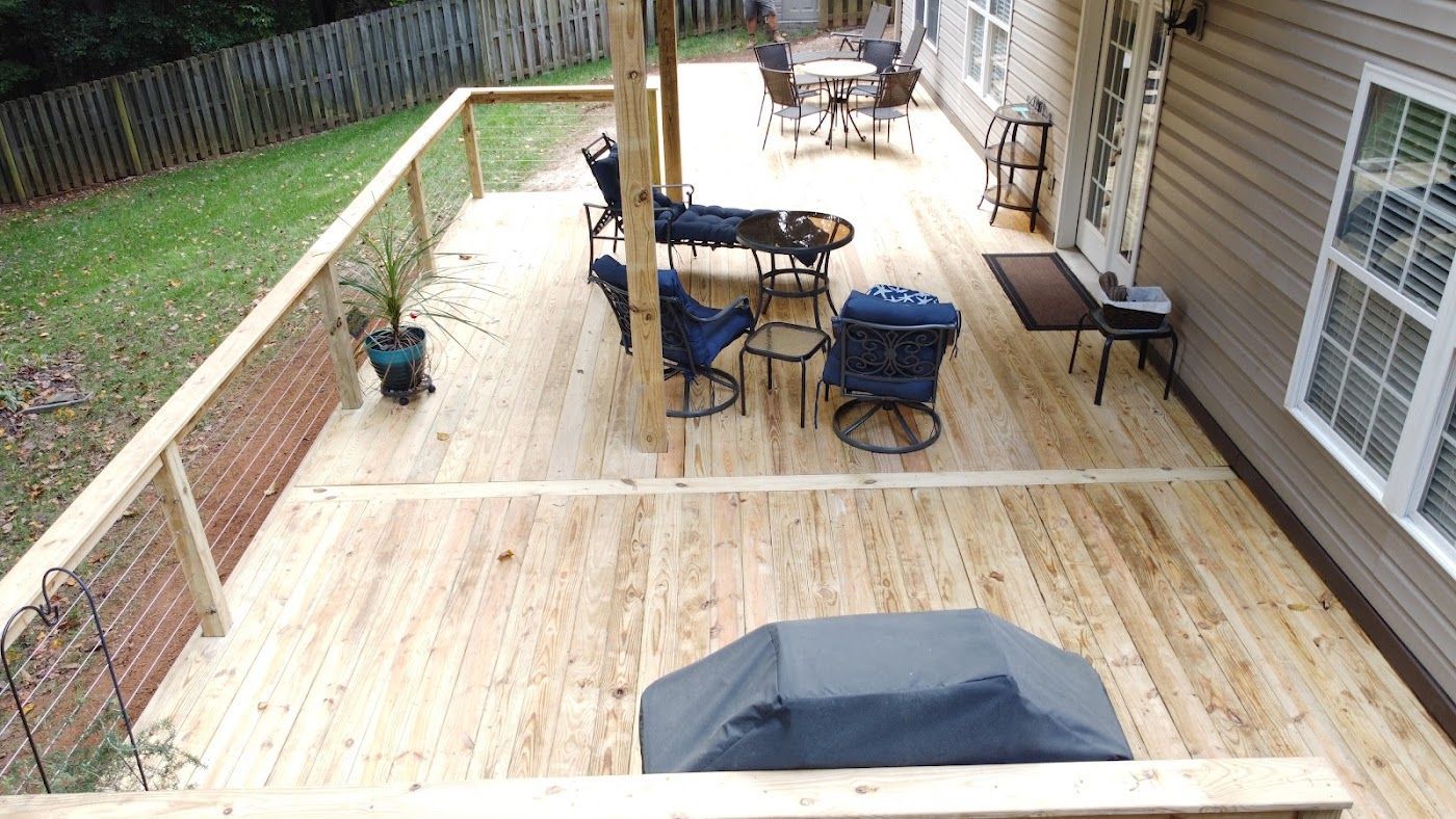 Wooden deck with various furniture; a grill, chairs, and table. Surrounding fence and house siding.