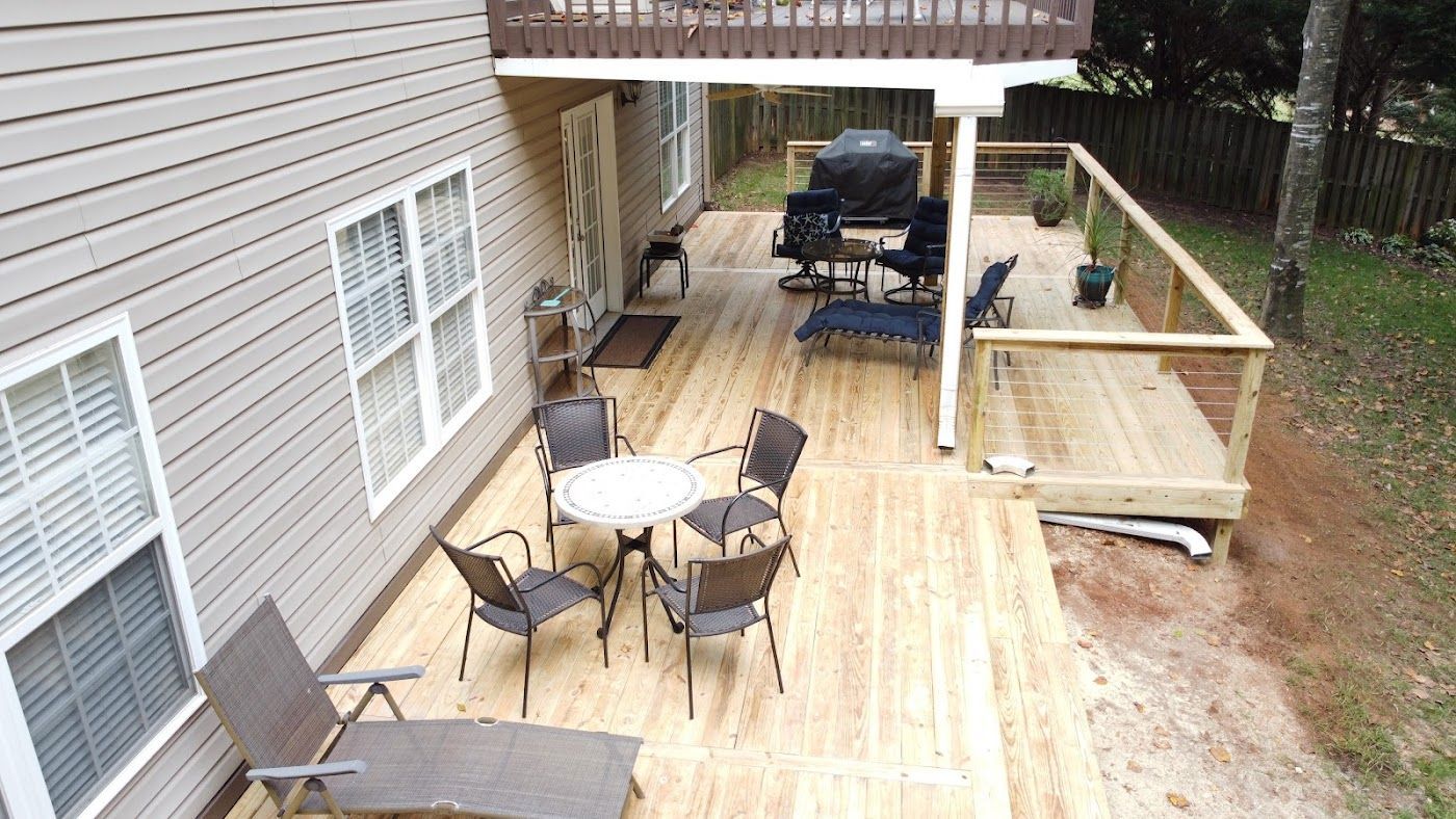 Wooden deck attached to a house with outdoor furniture and a grill.