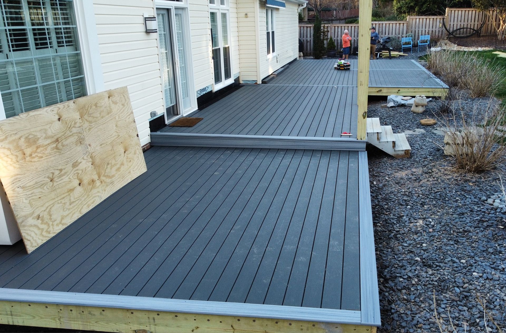 Newly constructed deck with gray composite decking, leading to a smaller deck section and yard.
