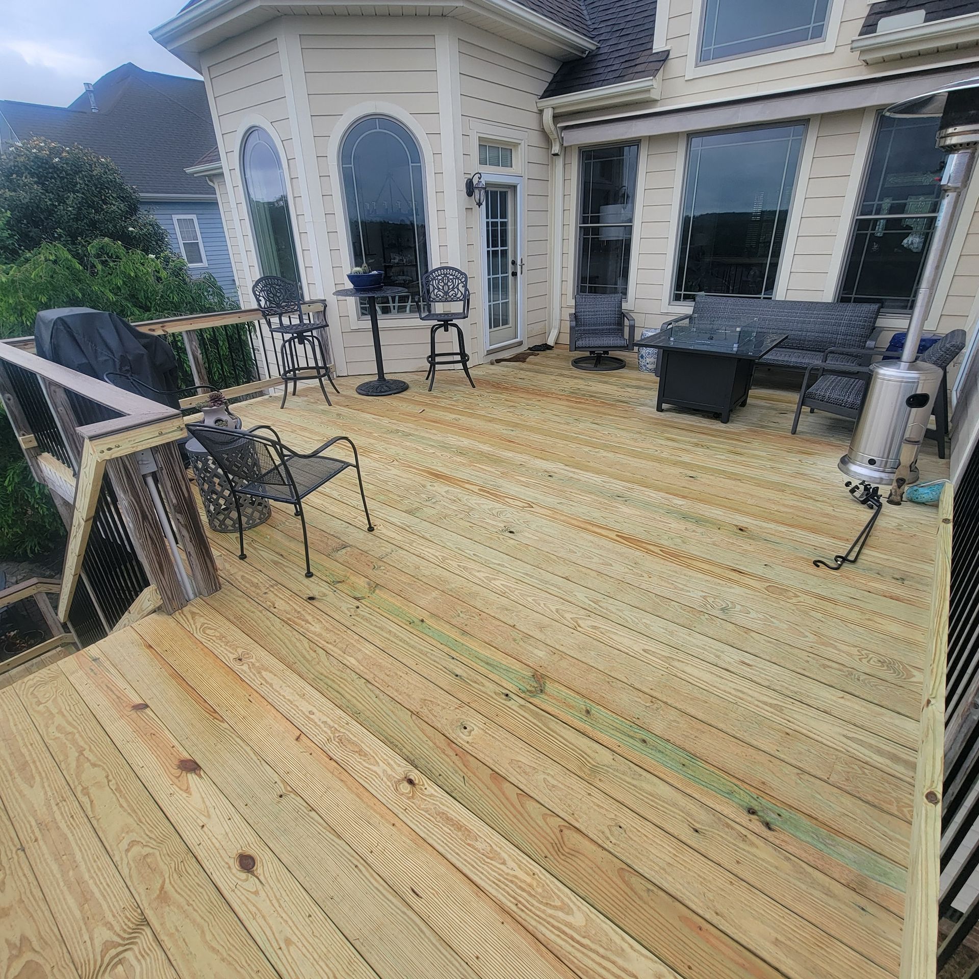 Wooden deck with patio furniture next to a two-story beige house.