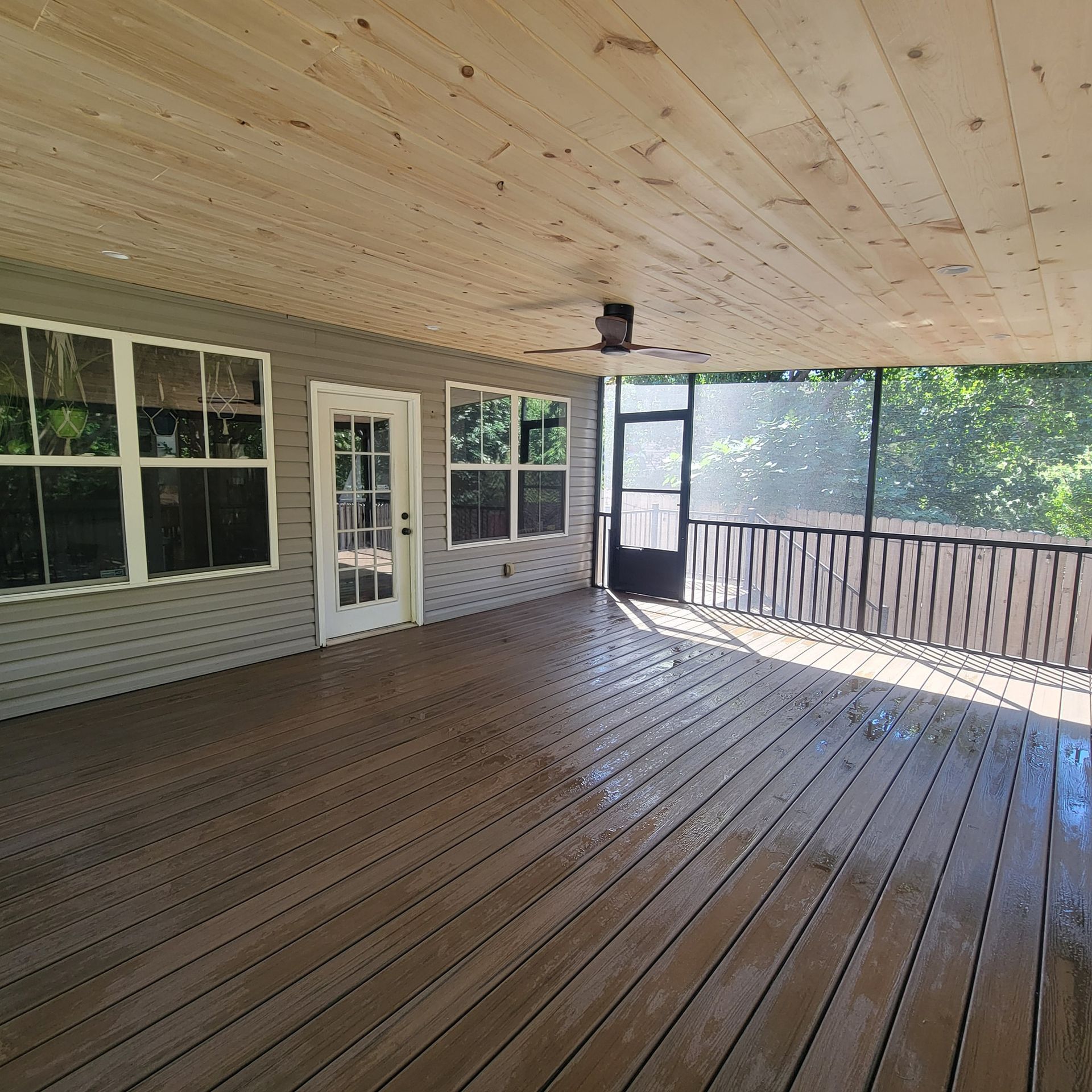 Covered outdoor patio with a wood ceiling, wood floor, gray walls, and screened enclosure.