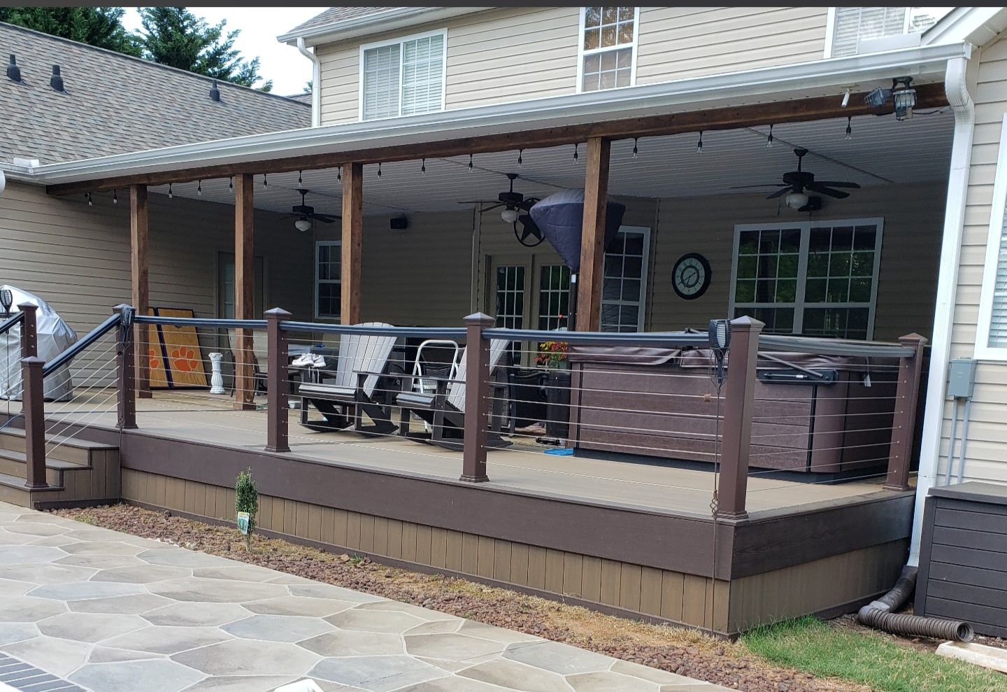 Newly built gray composite deck with house in background, plywood on deck.