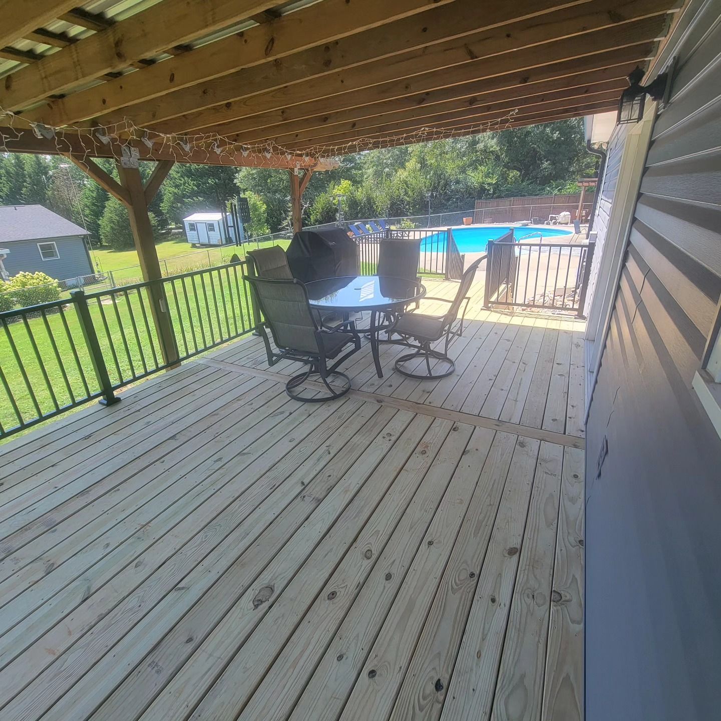 Wooden deck with outdoor furniture, overlooking a pool.