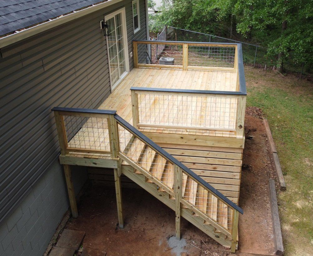 Wooden deck with stairs attached to a house with a sliding glass door.