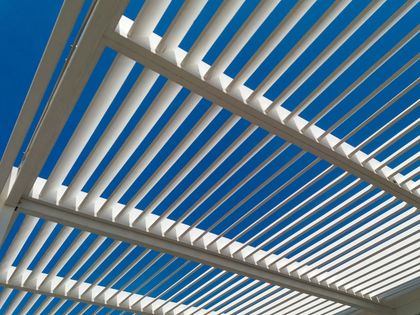 White slatted pergola against a bright blue sky.