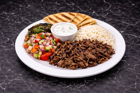 Plate of Greek food: sliced meat, rice, salad, grilled pita bread, and tzatziki sauce.