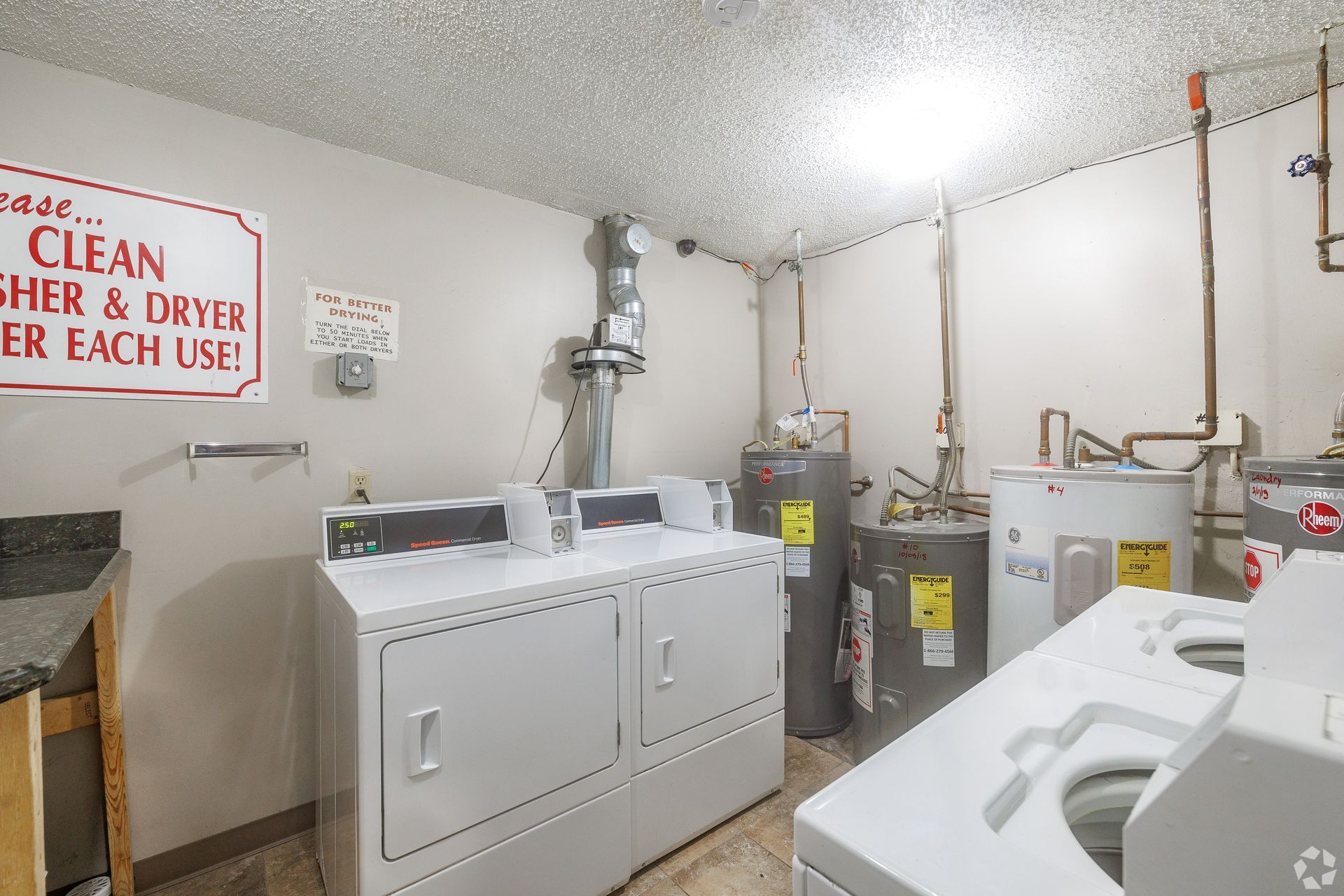 Laundry room with washing machines, dryers, utility sink, and a “clean dryer” sign