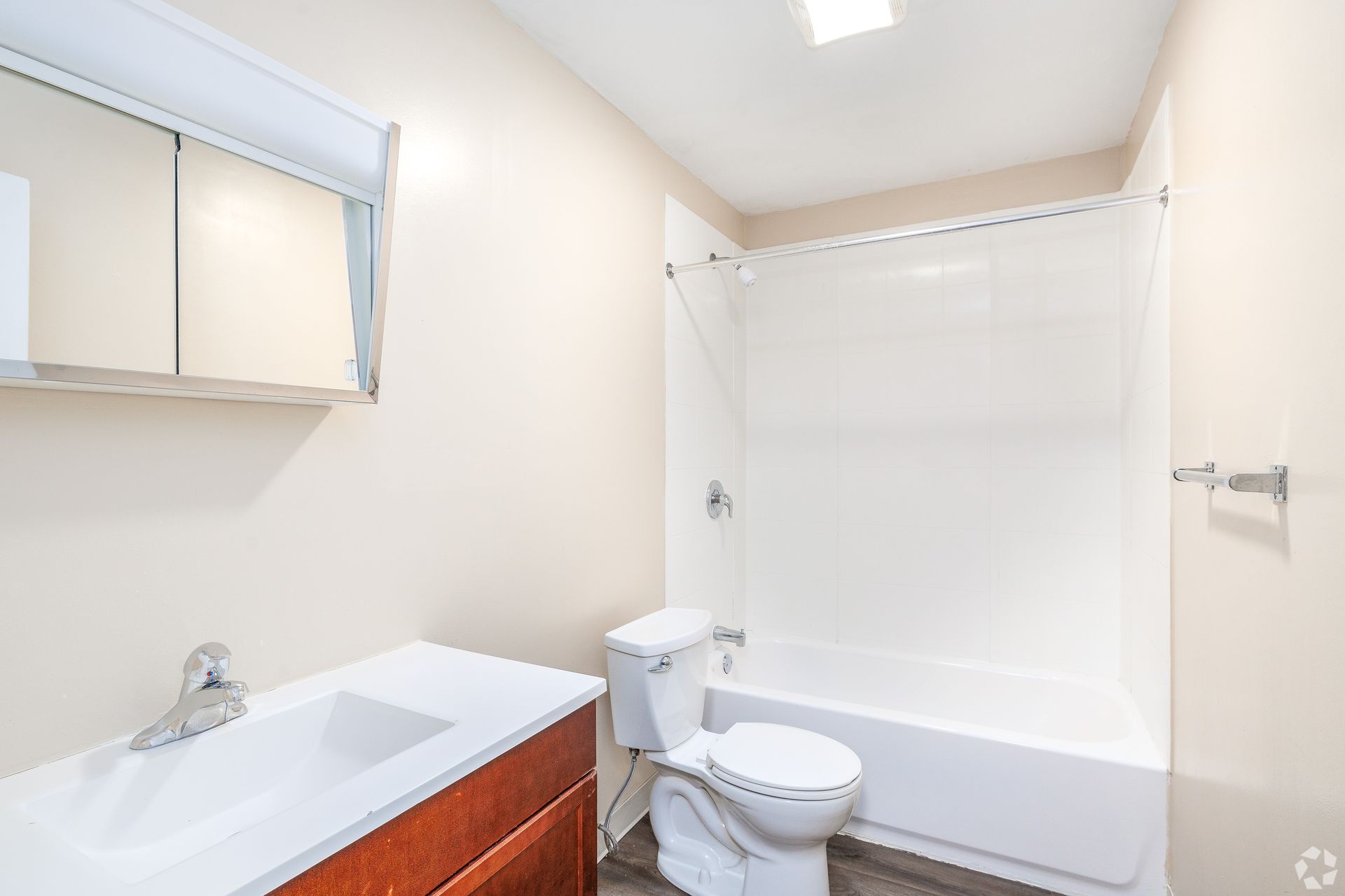 Bright white bathroom with vanity, mirror, toilet, and bathtub with shower curtain.