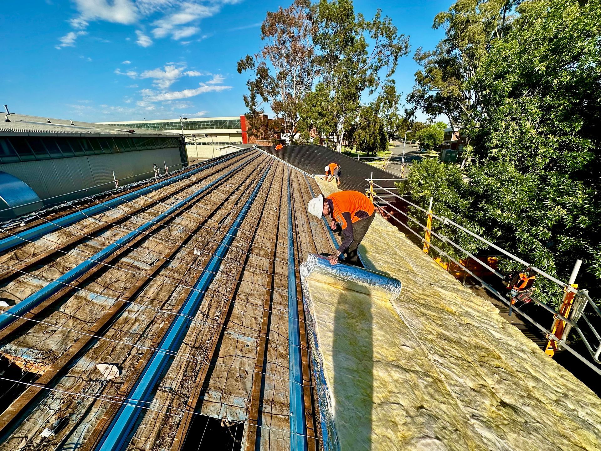 A Man is re-roofing a house — Essential Roofing and Plumbing in Wagga Wagga, NSW