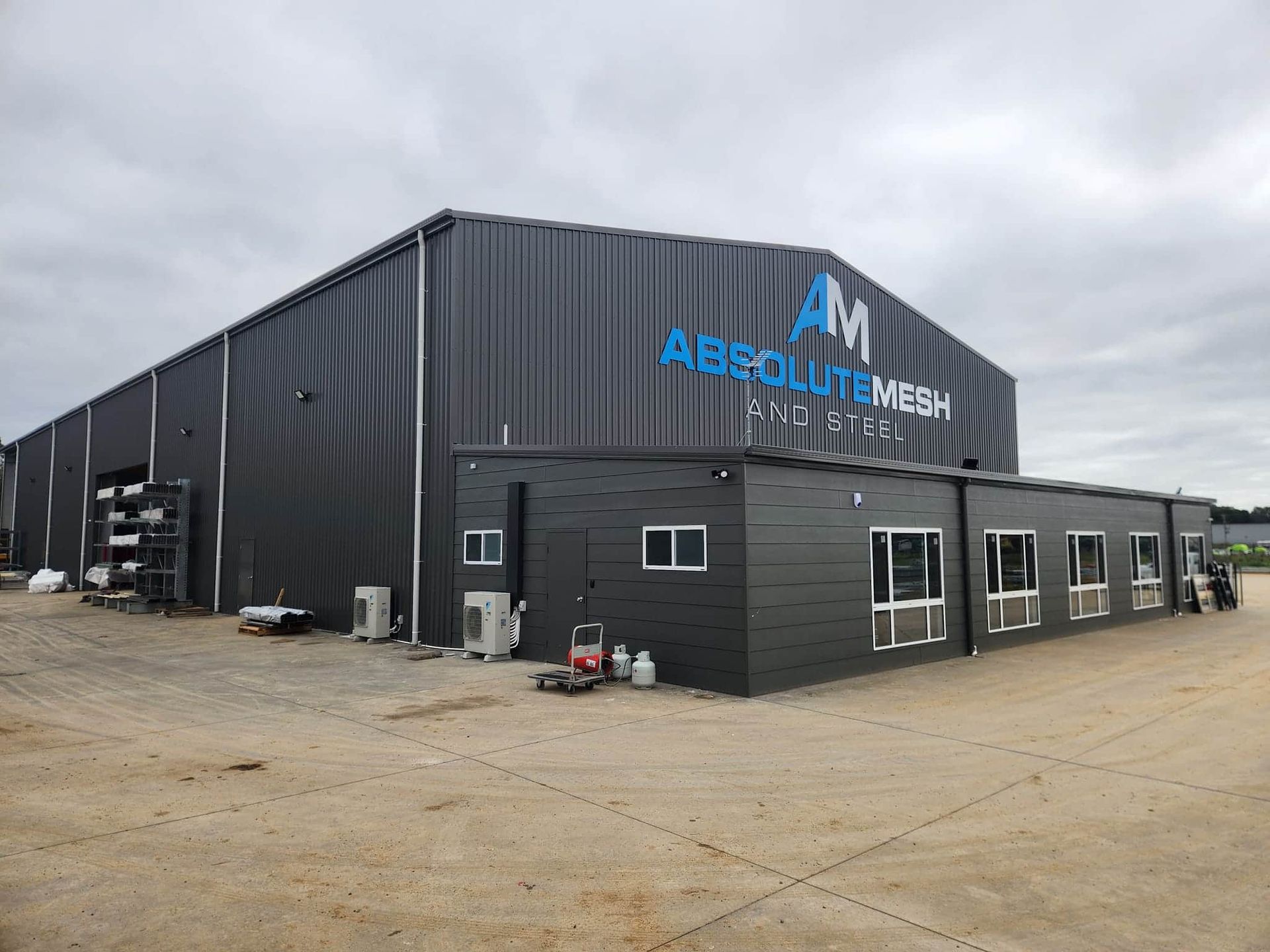 A Large Black Building With the Word Absolute Mesh on It — Essential Roofing and Plumbing in Wagga Wagga, NSW