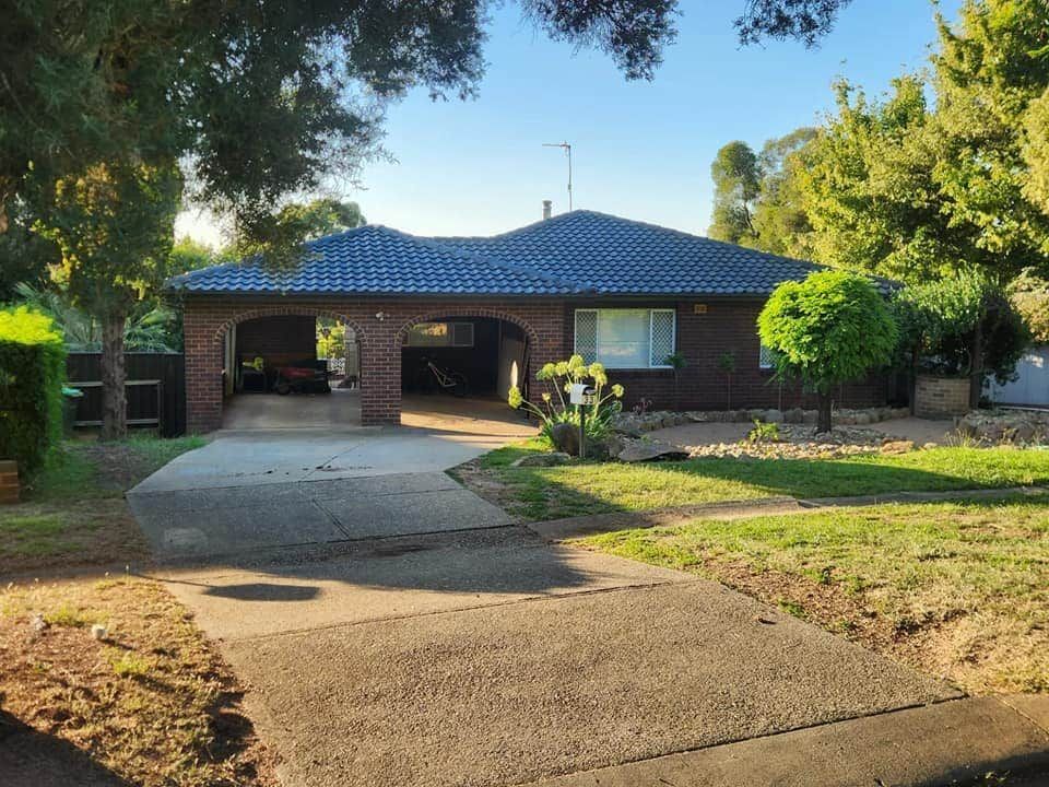 A Brick House With a Blue Roof and a Driveway — Essential Roofing and Plumbing in Cootamundra, NSW